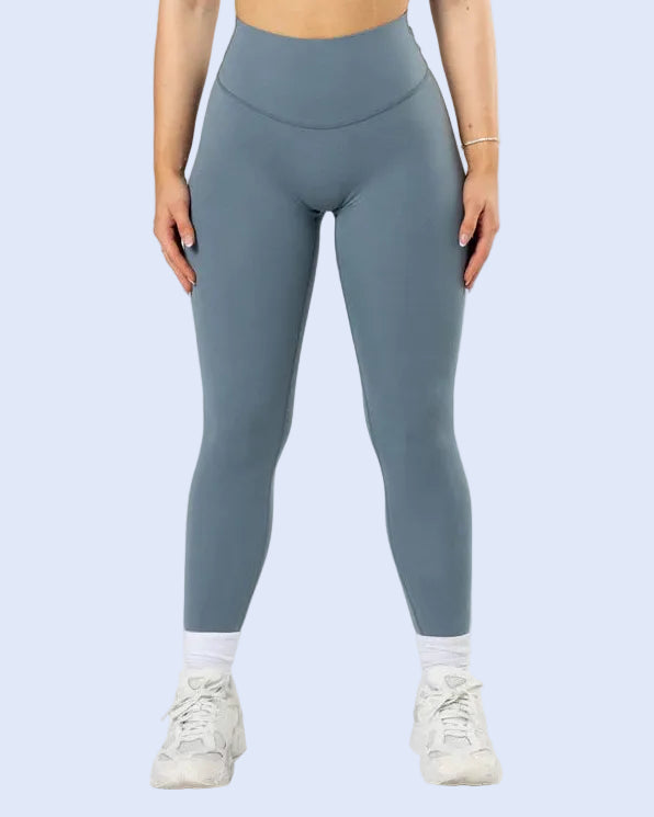 Person wearing blue leggings and a sports bra on a white background