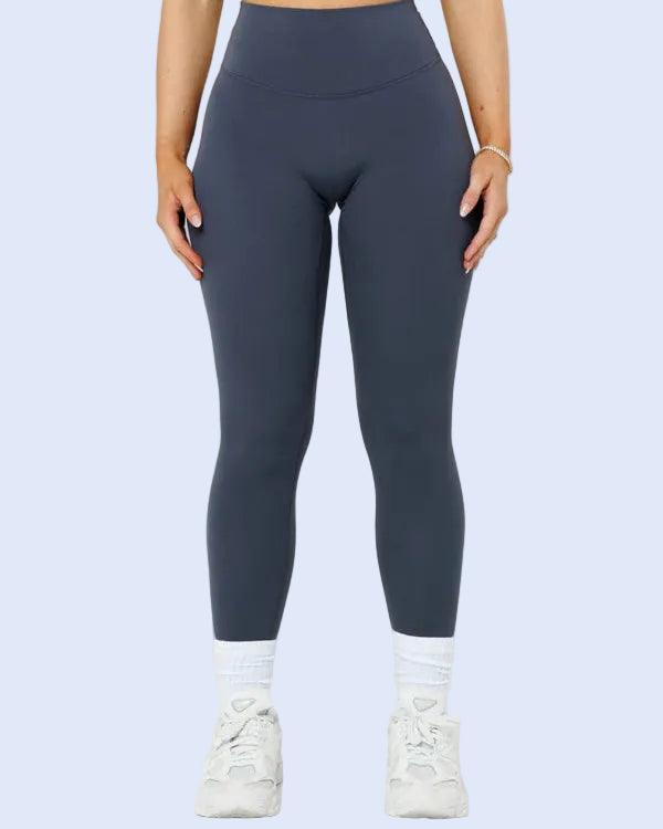 Person wearing dark gray leggings and white sneakers on a light gray background