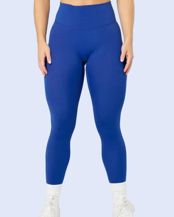 A model wearing bright royal blue high-waisted leggings, white crew socks, and white sneakers, shown from the waist down against a light gray studio background.