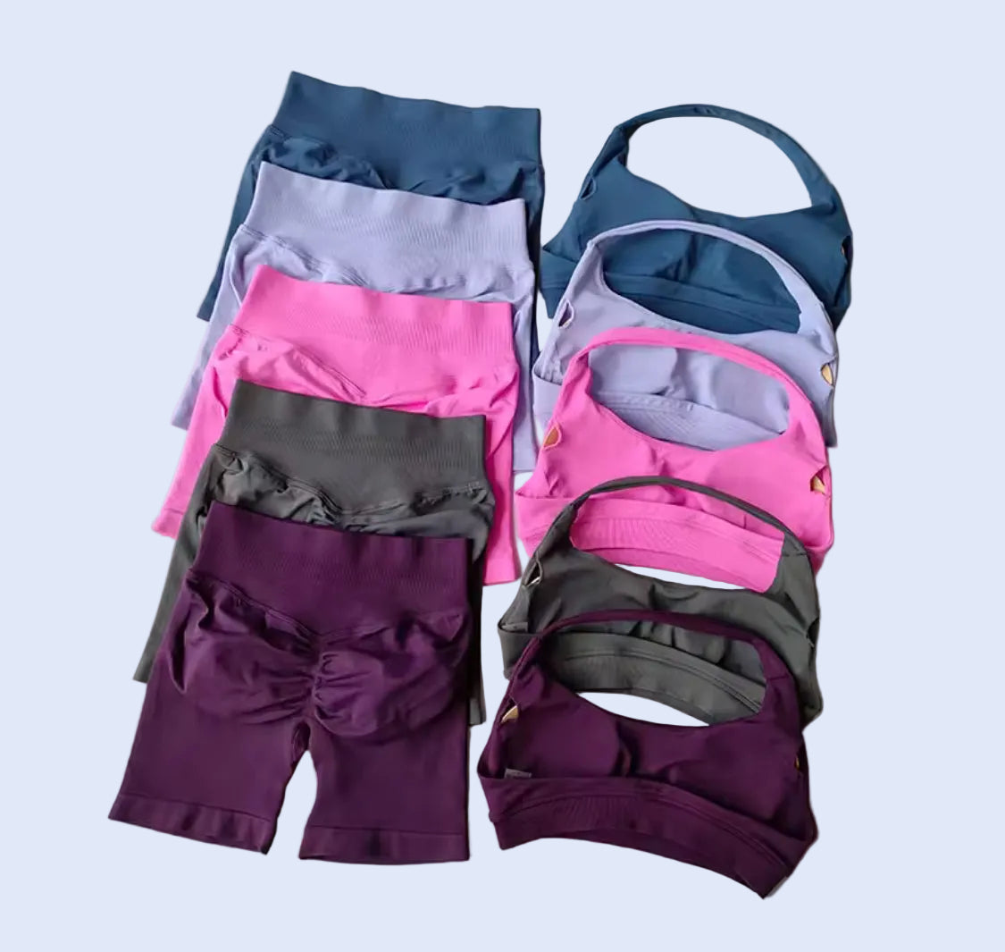 Stack of women's athletic wear including leggings and sports bras on a light blue background
