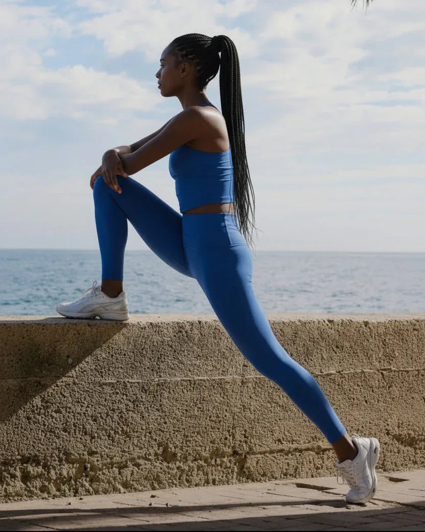 Woman_in_blue_athletic_wear_stretching_outdoors_by_the_sea