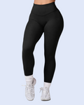Black high-waisted leggings worn by a model, paired with white socks and white sneakers, shown from the waist down against a light blue background.
