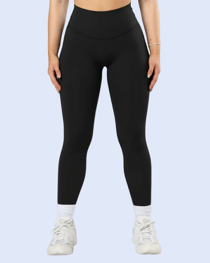 A model wearing black high-waisted leggings, white crew socks, and white sneakers, shown from the waist down against a light blue background.