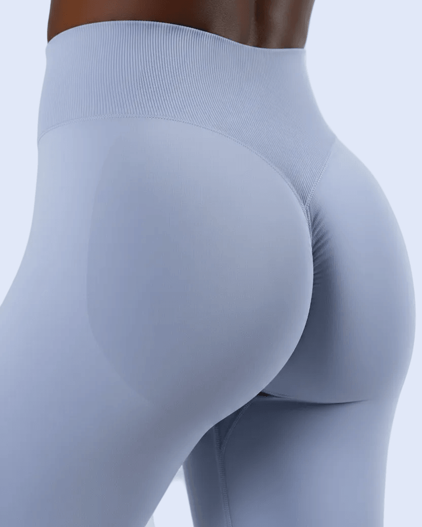 Close-up rear view of a model wearing high-waisted, form-fitting leggings in a pale periwinkle or light lavender-blue shade against a clean white background.
