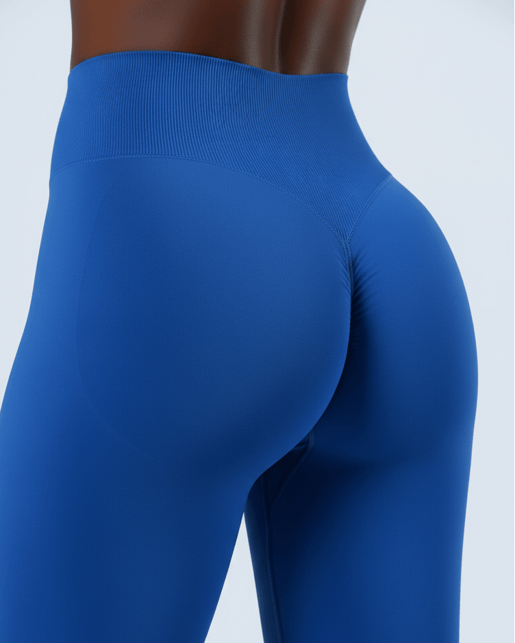 Close-up of a model wearing high-waisted blue leggings, showing the back and side fit against a light gray studio background.