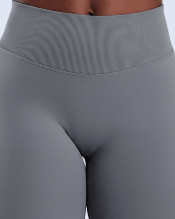 Close-up of a person wearing high-waisted gray leggings against a light blue background.