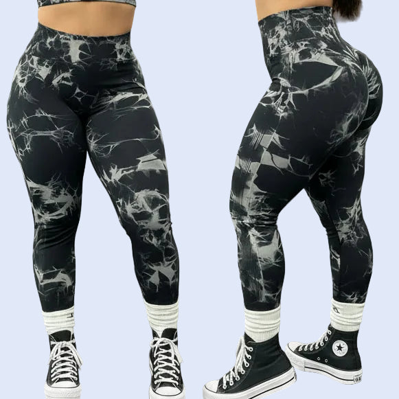 Person wearing black and white patterned leggings with black sneakers in a gym setting