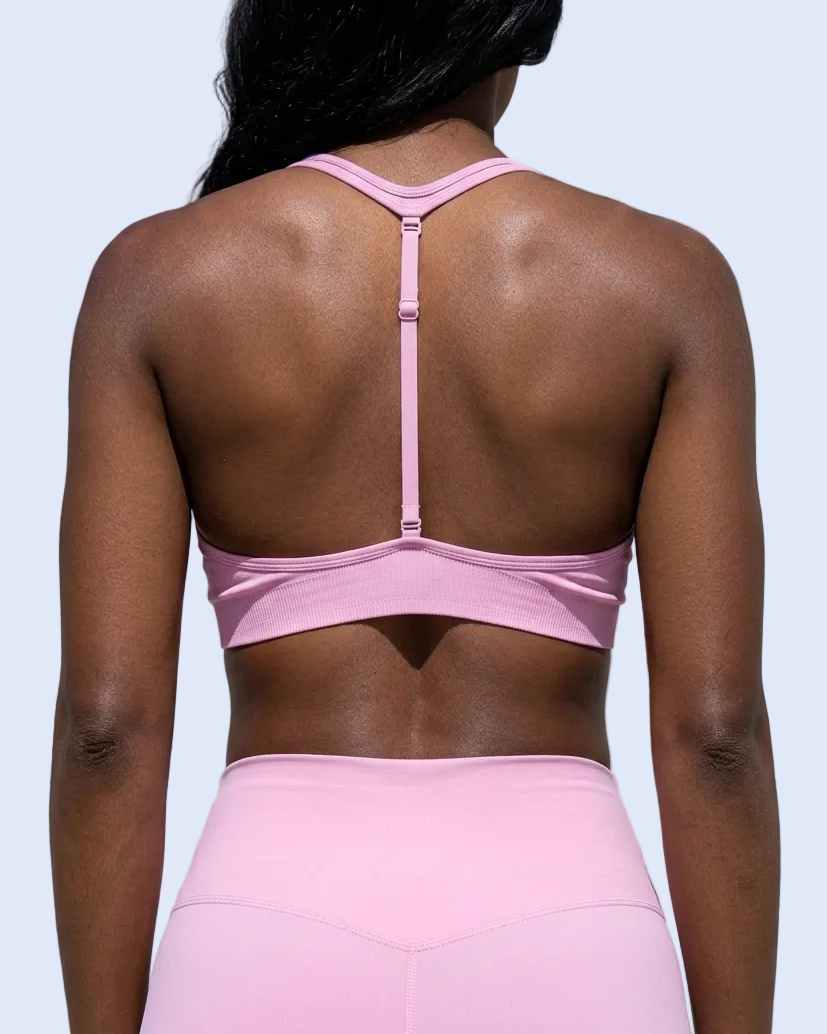 Straight-on back view with model facing away, focused on the pink bra’s open back and single adjustable center strap