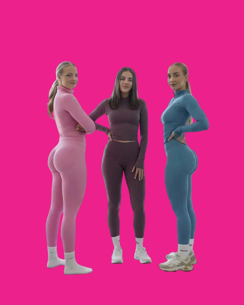 Three women in colorful matching outfits standing in a gym.